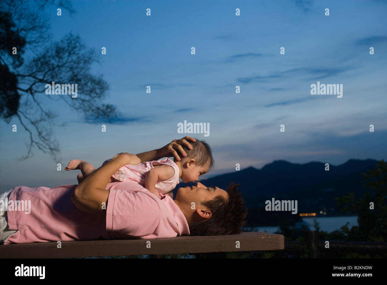 Jeune homme allongé sur un banc et jouant avec sa fille Banque D'Images