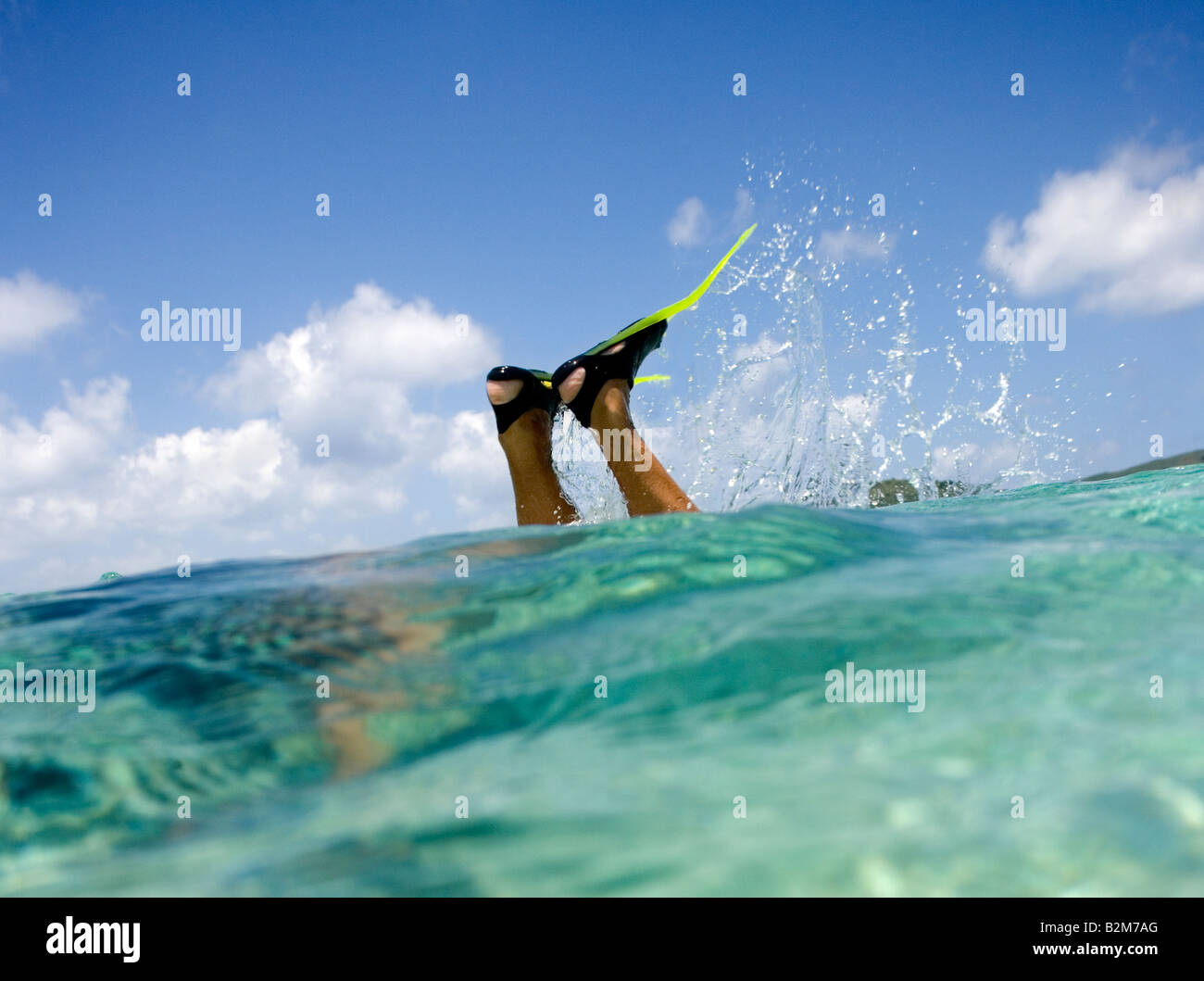 Un homme de la plongée libre dans les eaux claires des Caraïbes tous nous voir sont les nageoires et ses jambes qui le sort de l'eau Banque D'Images