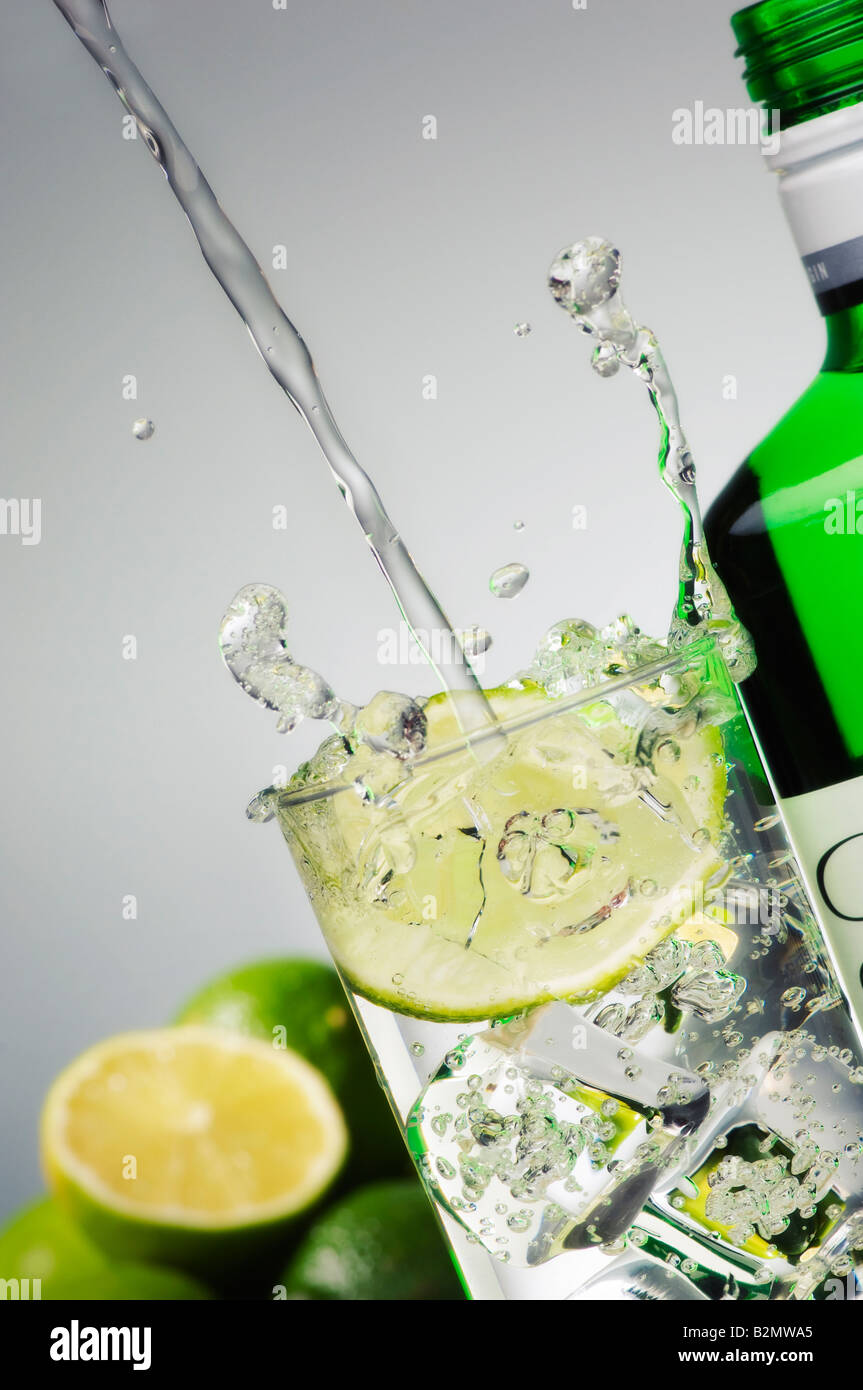 Gin Tonic et les projections dans le verre avec une bouteille sur le côté Banque D'Images