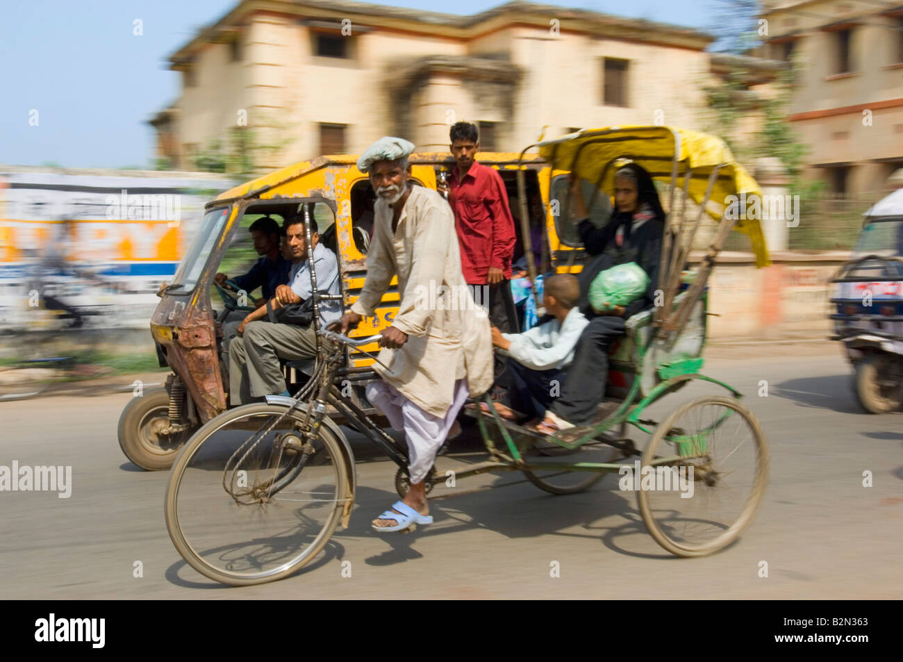 Pousse-pousse à vélo et auto rickshaw (tuk tuk) derrière avec les passagers à Varanasi. Vitesse d'obturation lente et le panoramique de flou. Banque D'Images