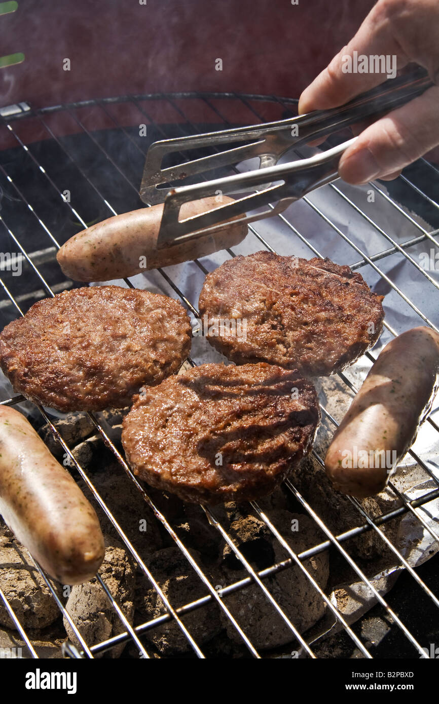 Saucisses et beefburgers sur un barbecue, UK. Banque D'Images