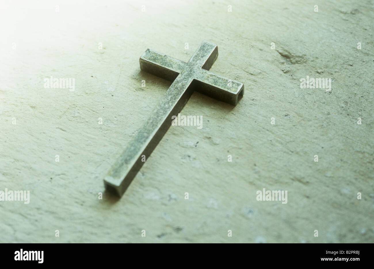 Crucifix en laiton terni simple couché sur le rebord en pierre peint crème ou de niche Banque D'Images