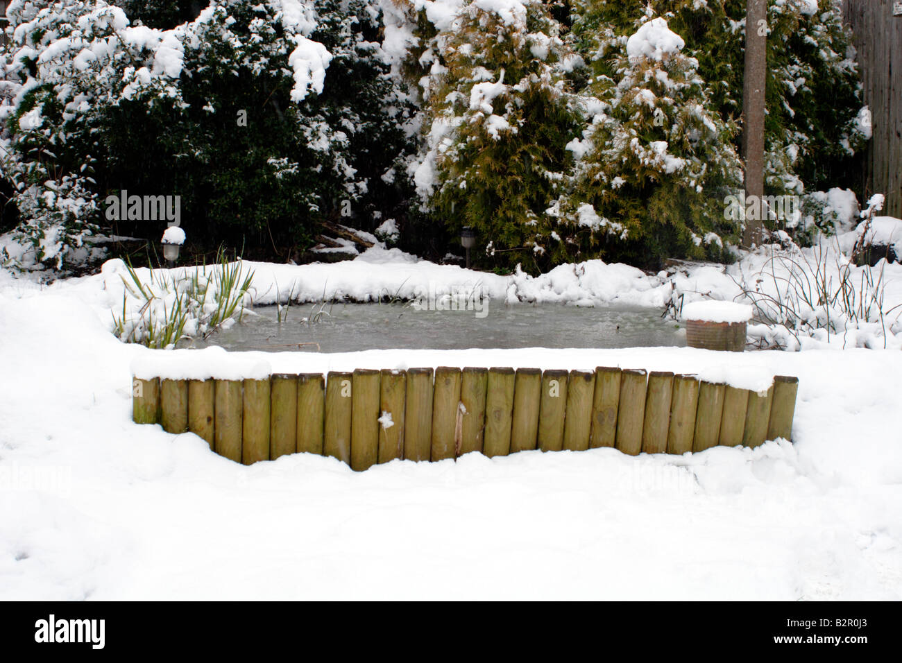 Le jardin couvert de neige, sur l'étang glacé, UK Banque D'Images