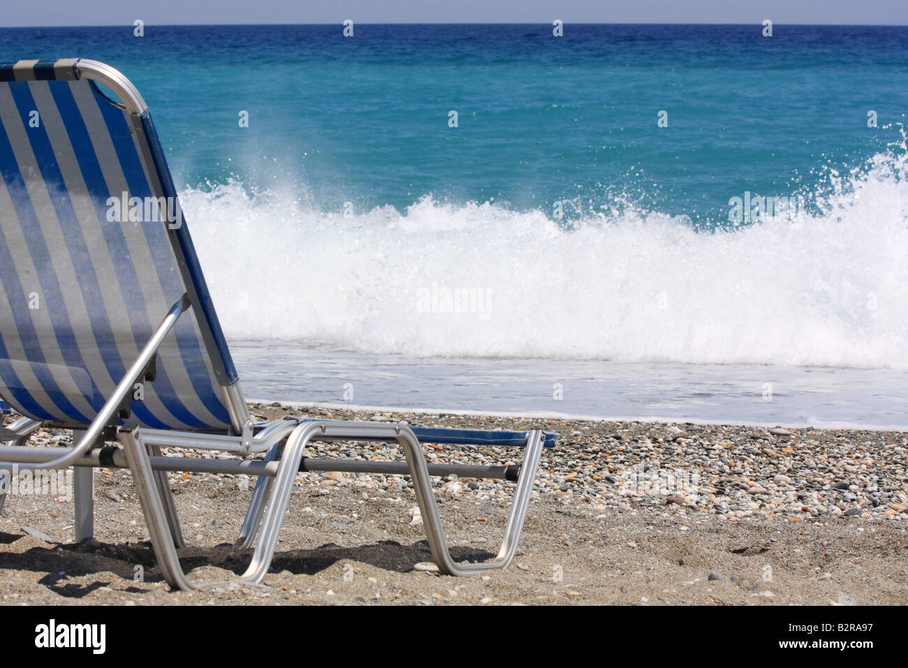 Une plage vide chaise en face d'une vague déferlante Banque D'Images