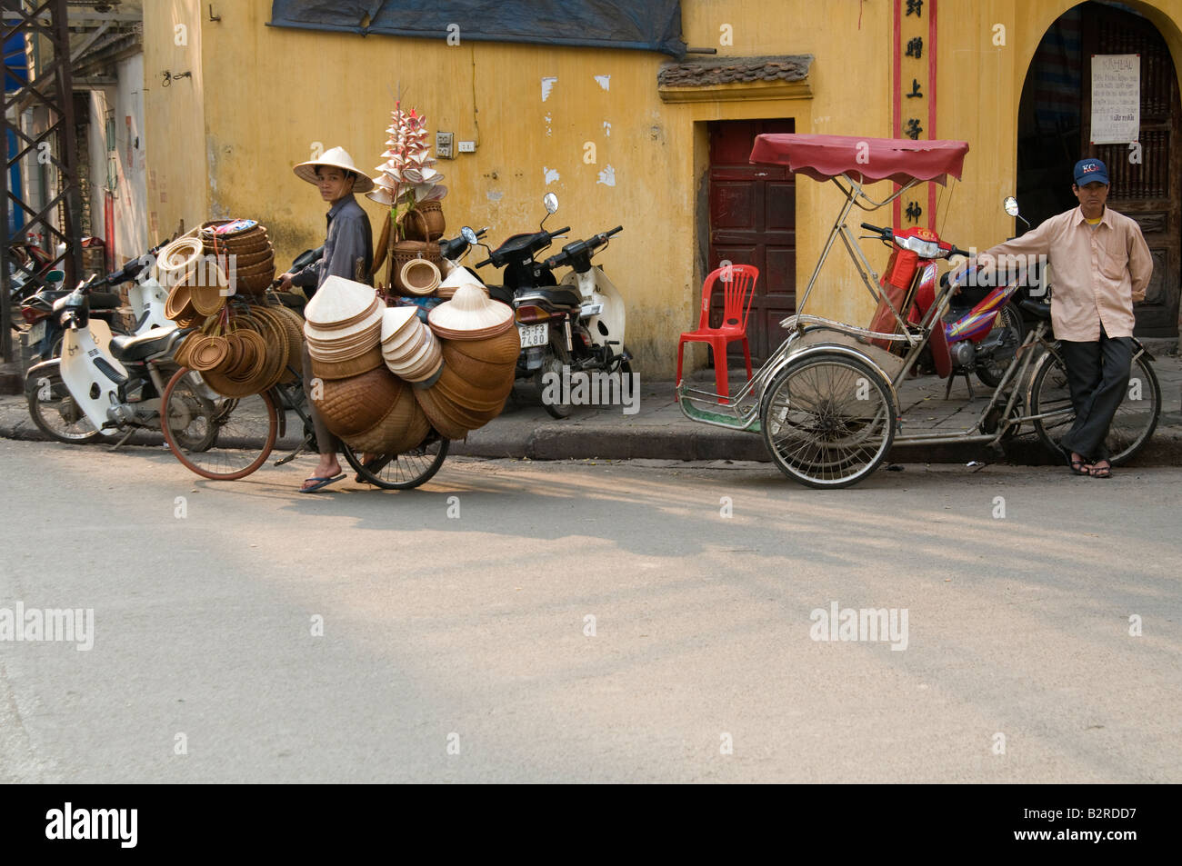 Hat vendeur et un chauffeur de taxi à la recherche à l'appareil photo dans le vieux quartier de Hanoi Vietnam Banque D'Images