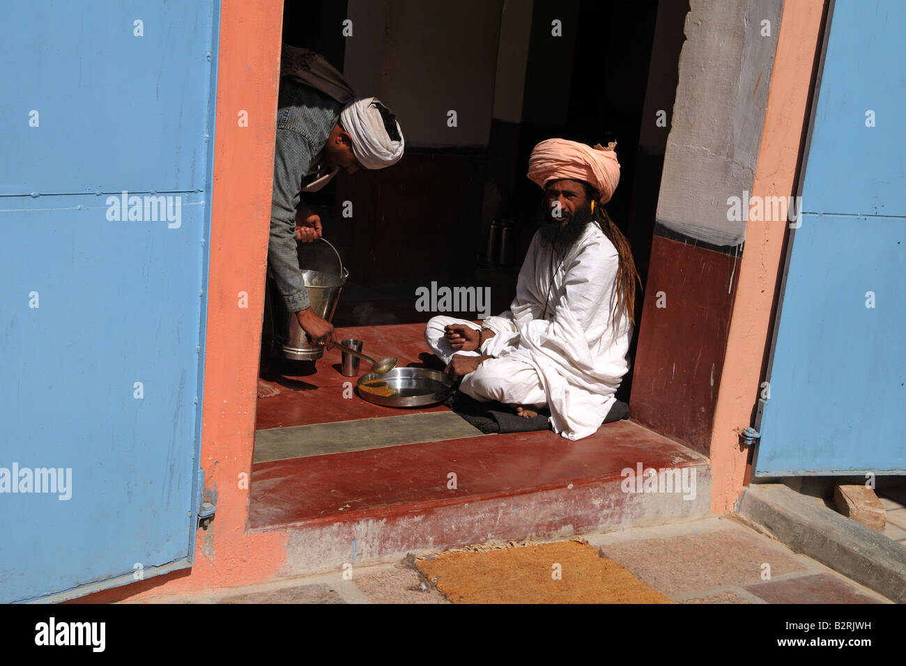 Un Sadhu bénéficie d'dhal et Chapati pour déjeuner dans un petit temple au Rajasthan, Inde Banque D'Images