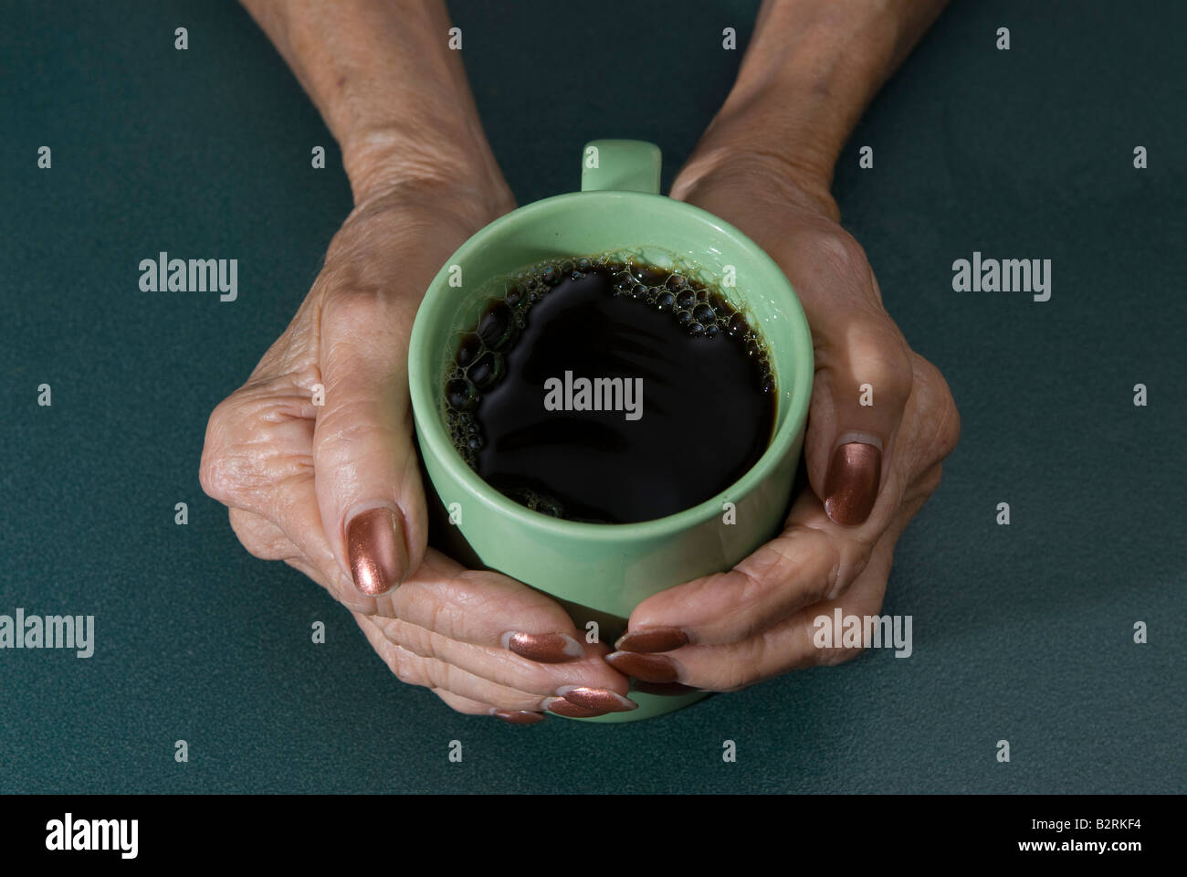 Femme mature s mains berçant coffee mug Banque D'Images