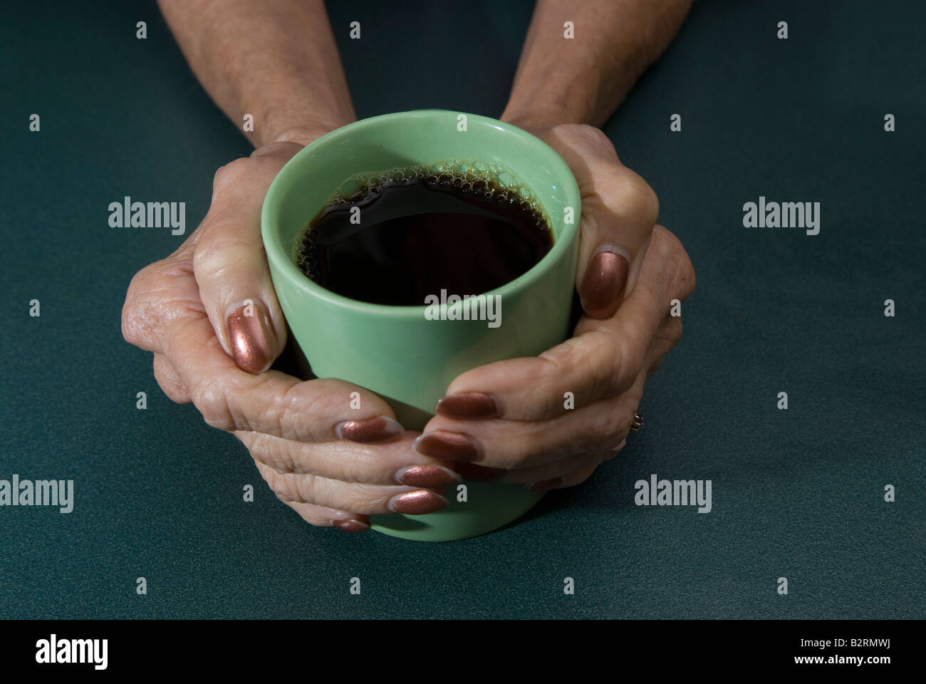 Femme mature s mains berçant coffee mug Banque D'Images