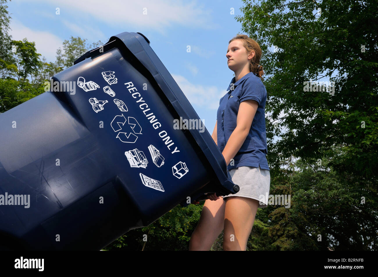 Jeune fille sortant le bac de recyclage bleu à la personne à la rue à Toronto Banque D'Images