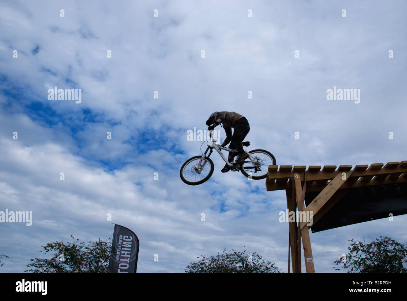 Jeune homme / adolescent saute d'une plate-forme équitation un vélo de montagne à une exposition d'équitation. Banque D'Images
