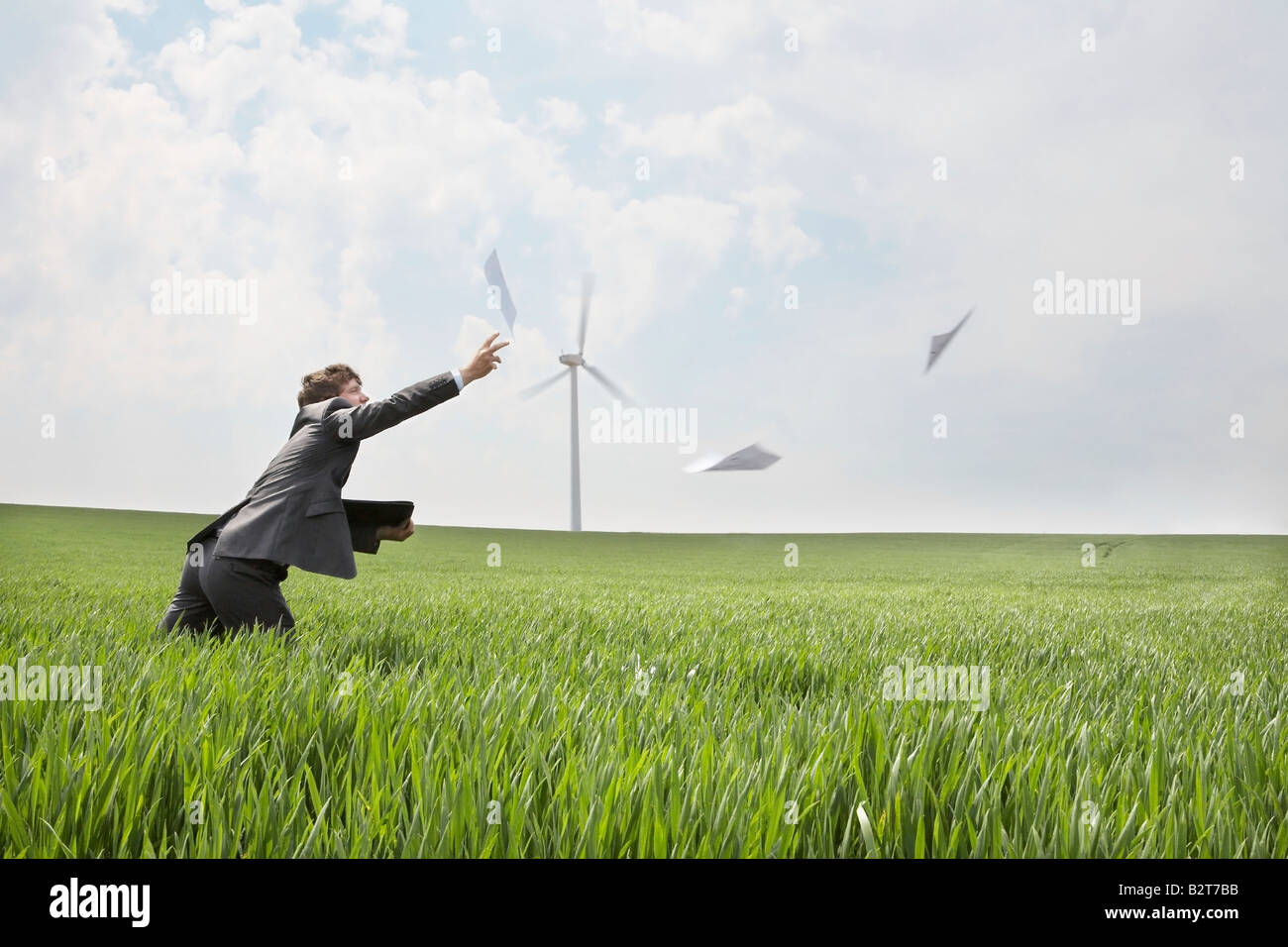 Man chasing papers on wind farm Banque D'Images