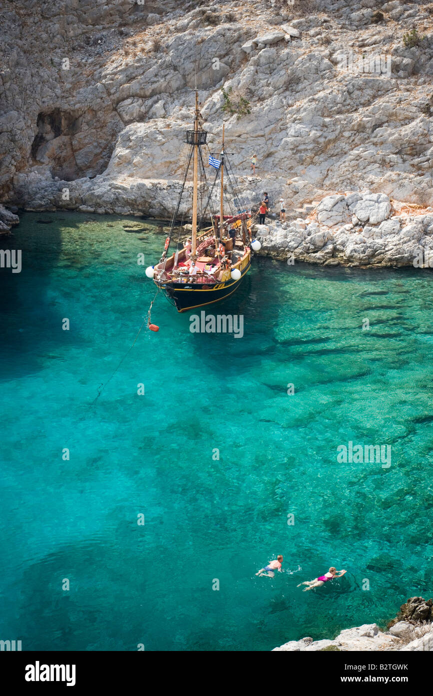 La natation de personnes dans une baie de Kalymnos à côté d'un bateau à voile, Grèce Banque D'Images