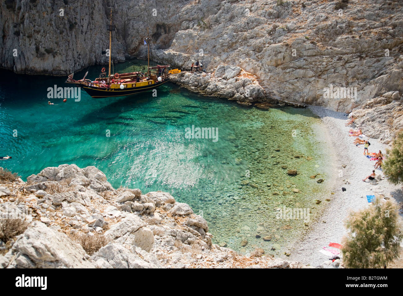 La natation de personnes dans une baie de Kalymnos à côté d'un bateau à voile, Grèce Banque D'Images
