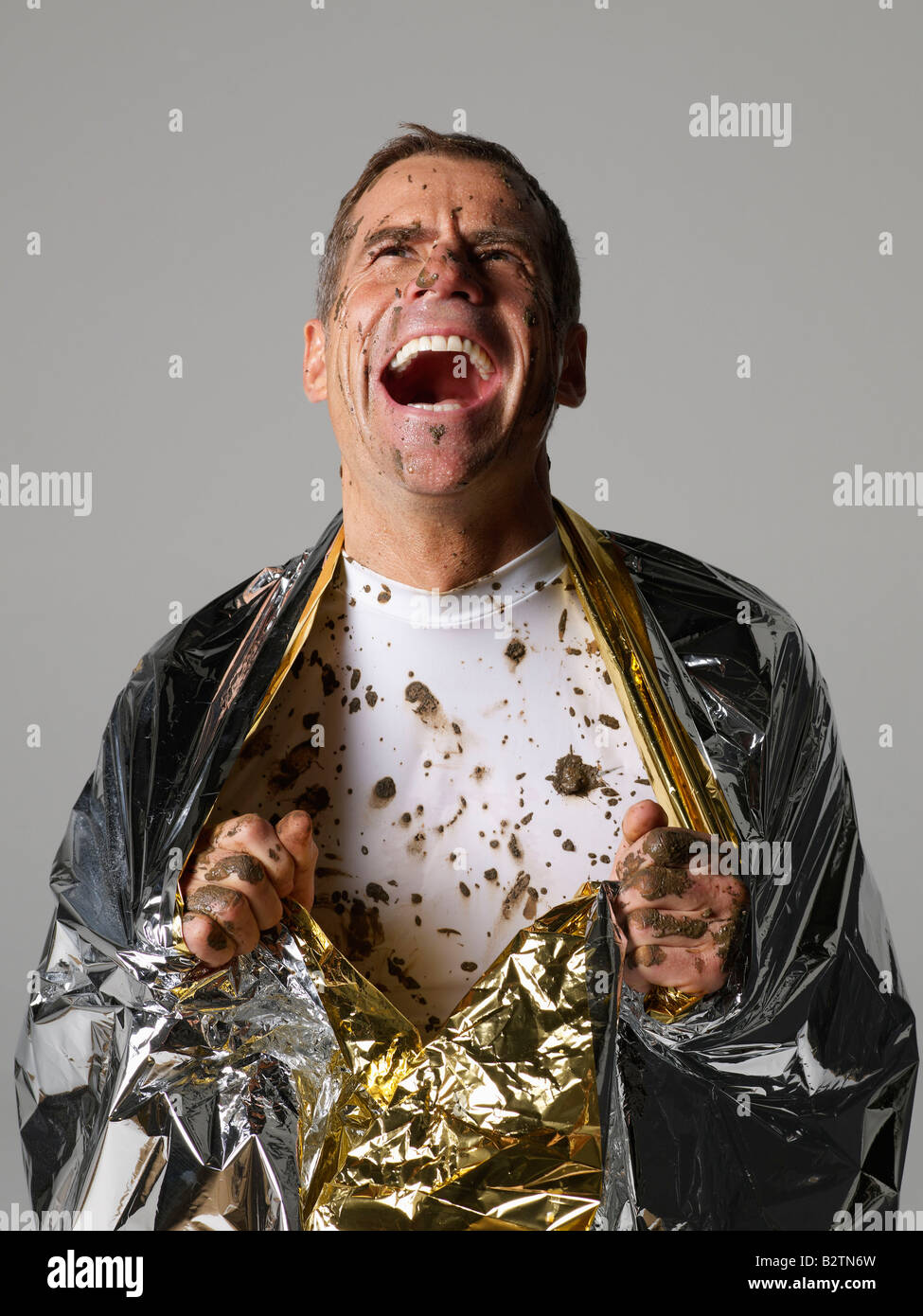 L'homme couvert de boue avec une couverture thermique Banque D'Images