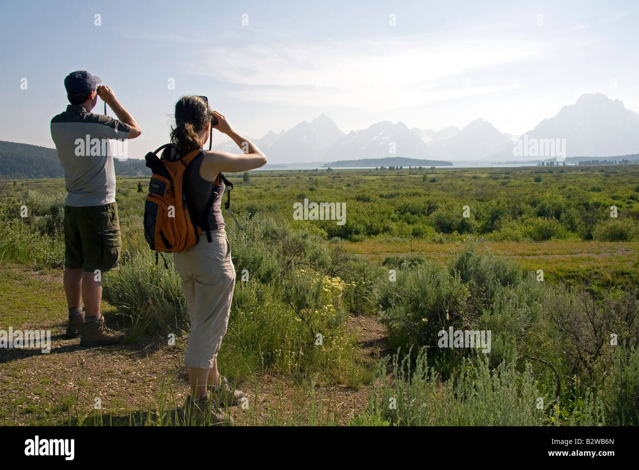 Les touristes l'affichage de la chaîne Teton et Jackson Lake avec des jumelles à Grand Teton National Park Wyoming Banque D'Images