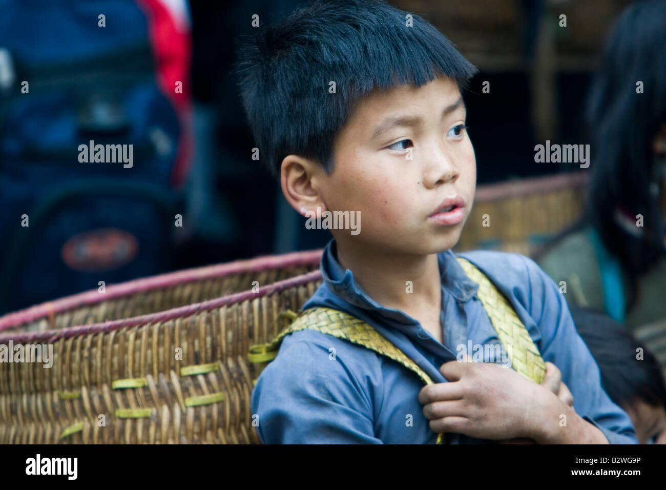 Hilltribe Hmong noir garçon avec l'épaule traditionnel panier attend à Sapa Vietnam Banque D'Images