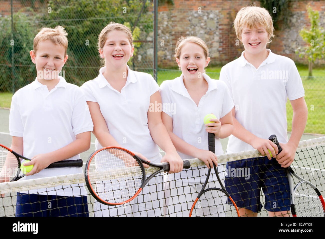 Quatre jeunes amis avec des raquettes de tennis sur smiling Banque D'Images