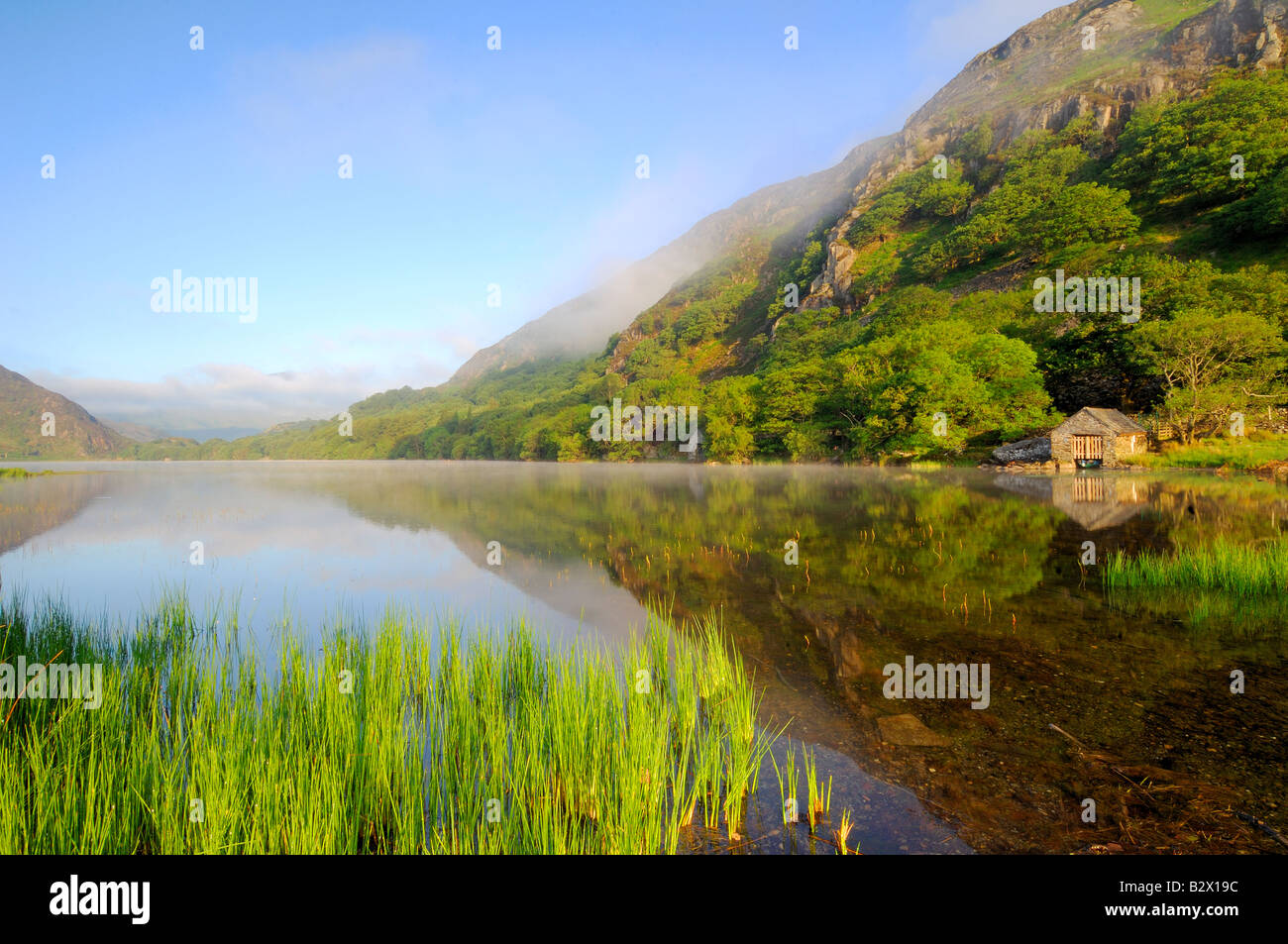 Un petit hangar à bateaux sur un beau matin brumeux et calme à Llyn Dinas dans le parc national de Snowdonia au nord du Pays de Galles Banque D'Images