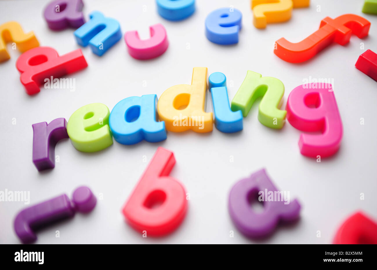 Lettres en plastique de couleur disposés à épeler la lecture chez les enfants Banque D'Images