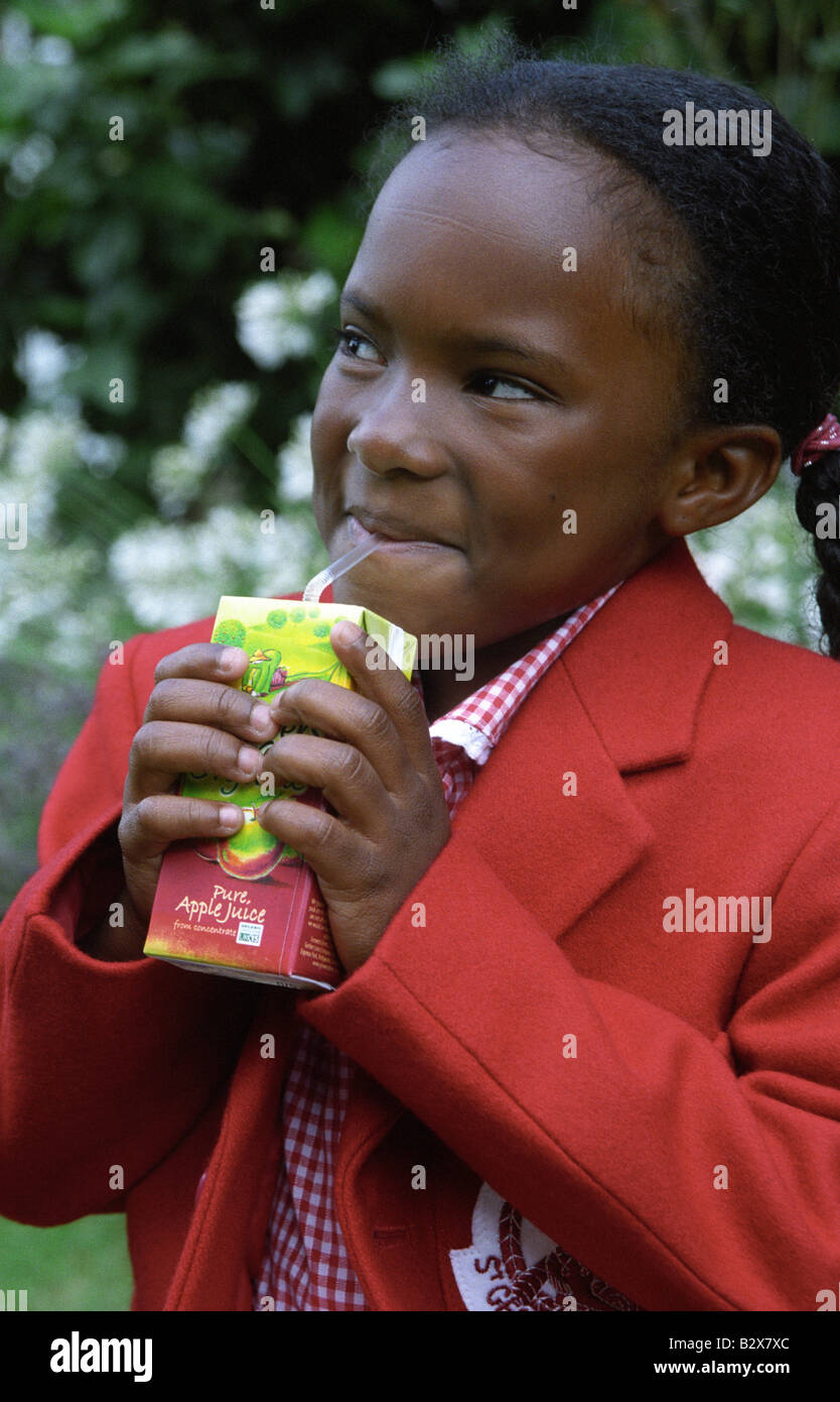 Petite écolière noir boire du jus de pomme bio. Banque D'Images