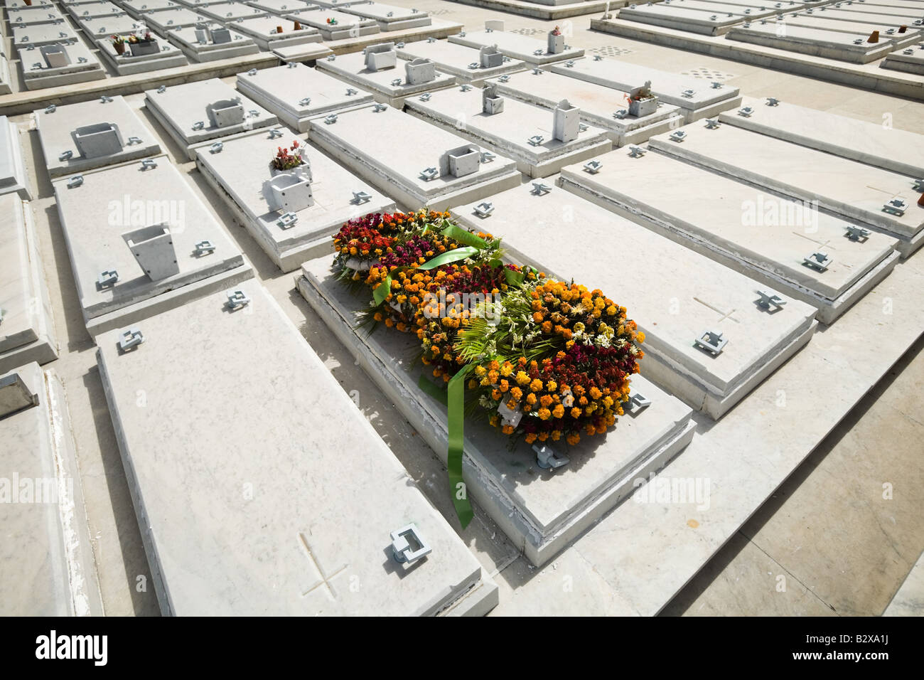Des couronnes de fleurs jeter sur l'un de plusieurs tombes identiques à la Nécropole Cristobal Colon cimetière à La Havane, Cuba Banque D'Images