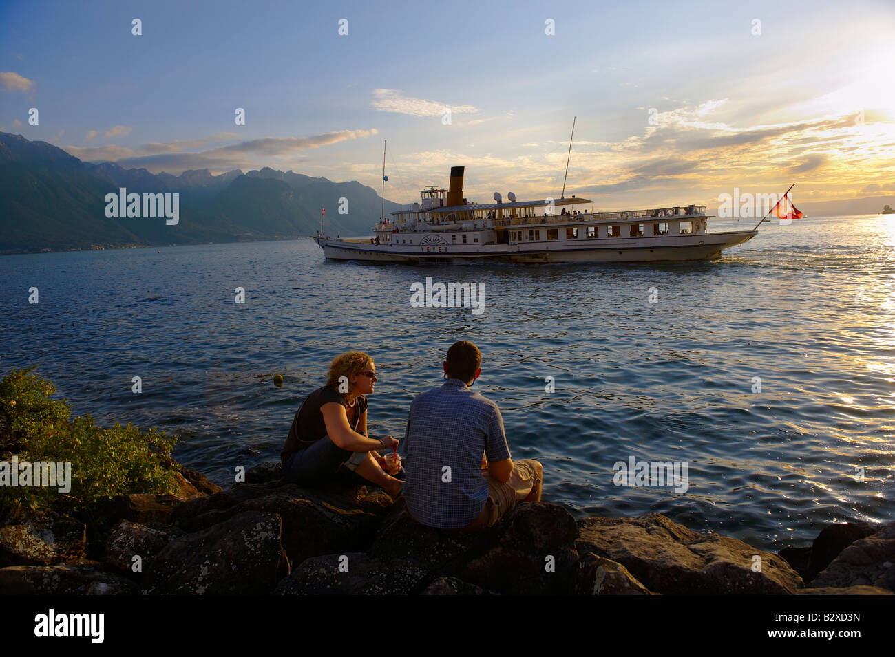 Jeune couple à la recherche d'un bateau à passagers sur le Lac Léman au coucher du soleil, Montreux, Vaud Suisse Banque D'Images