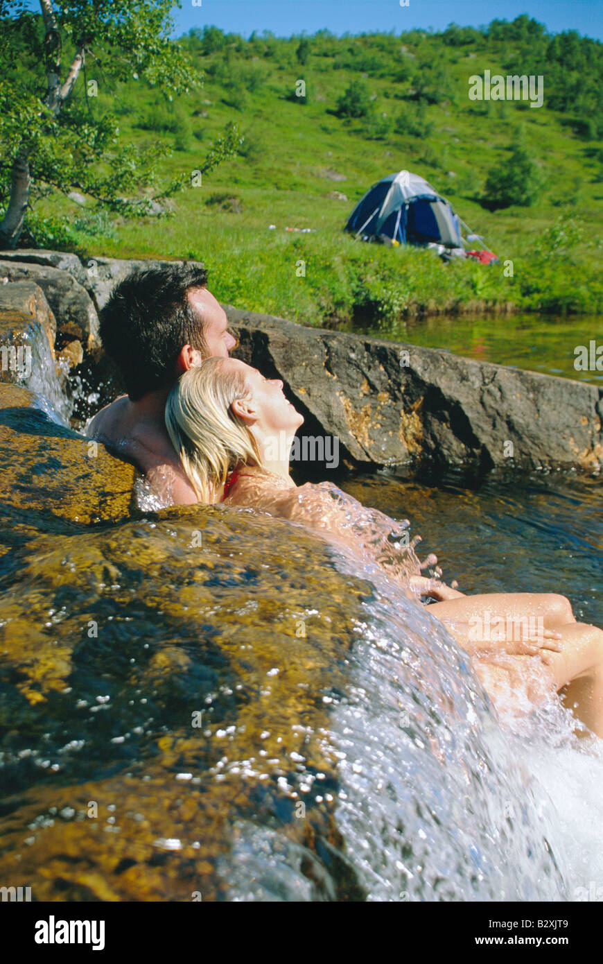 Couple outdoors par camping relaxing in stream Banque D'Images