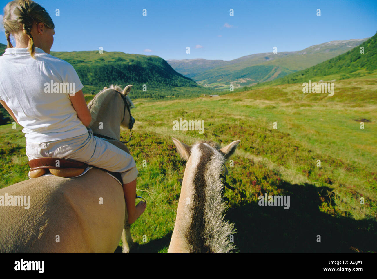 Woman outdoors riding horse dans emplacement panoramique avec un autre cheval à ses côtés Banque D'Images