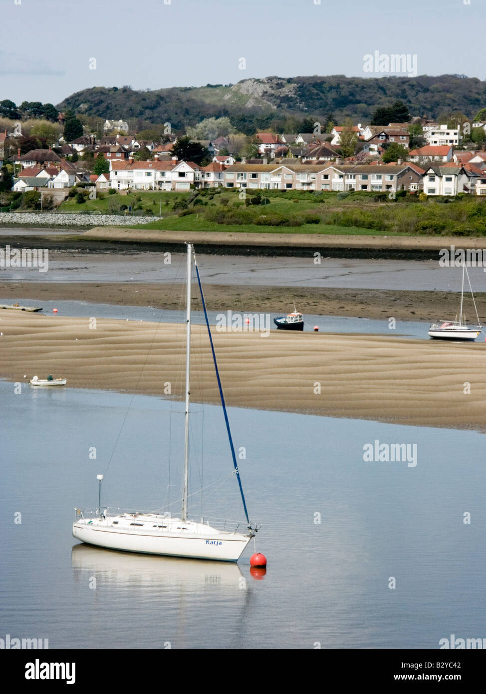 Yacht blanc et les petits bateaux ancrés par un banc de sable à marée basse dans le port de l'estuaire de Conwy, Conwy, au nord du Pays de Galles, Royaume-Uni Banque D'Images