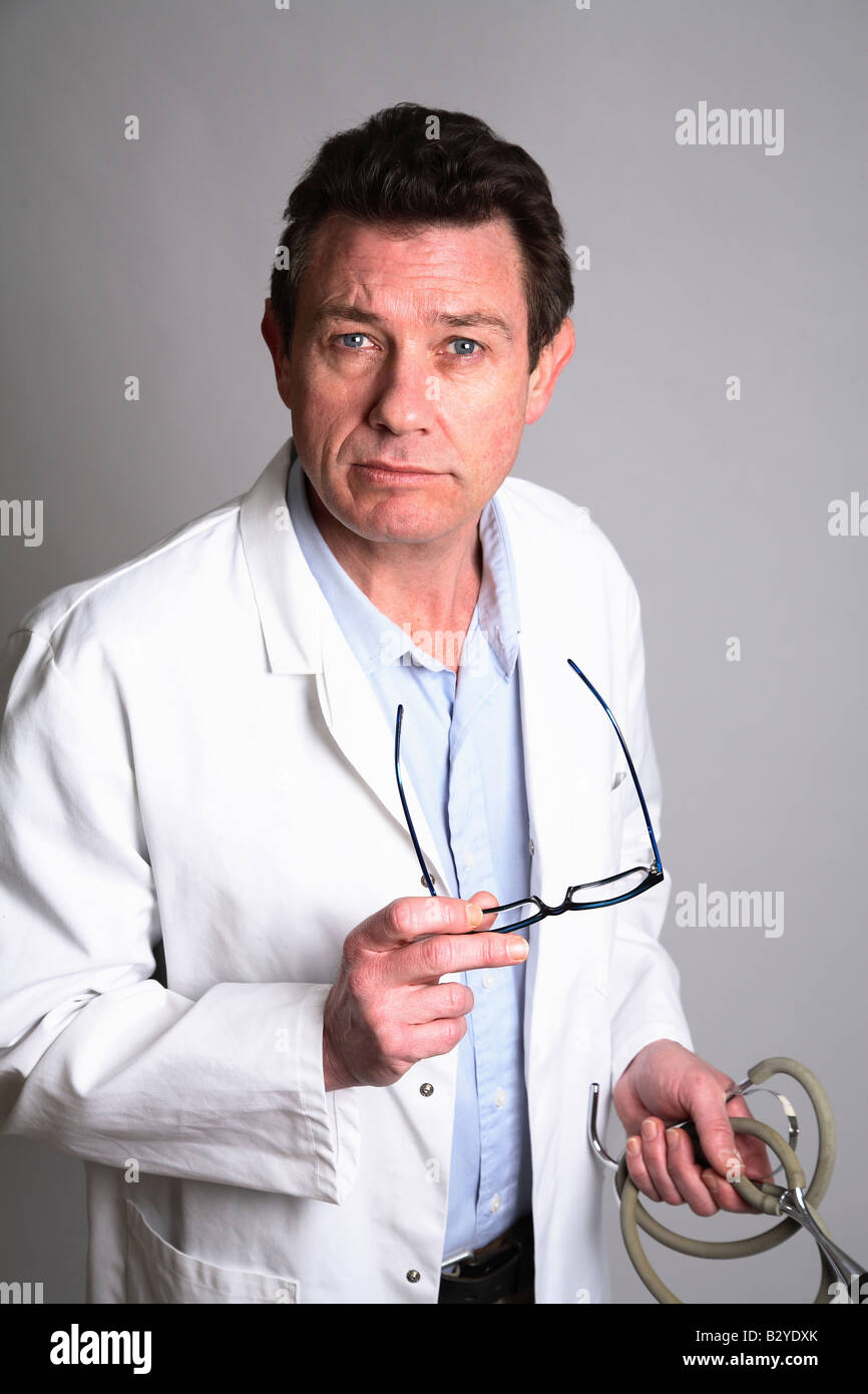 Homme de race blanche entre 40 et 46 médecin, holding de verres et d'un stéthoscope, looking at camera. Banque D'Images