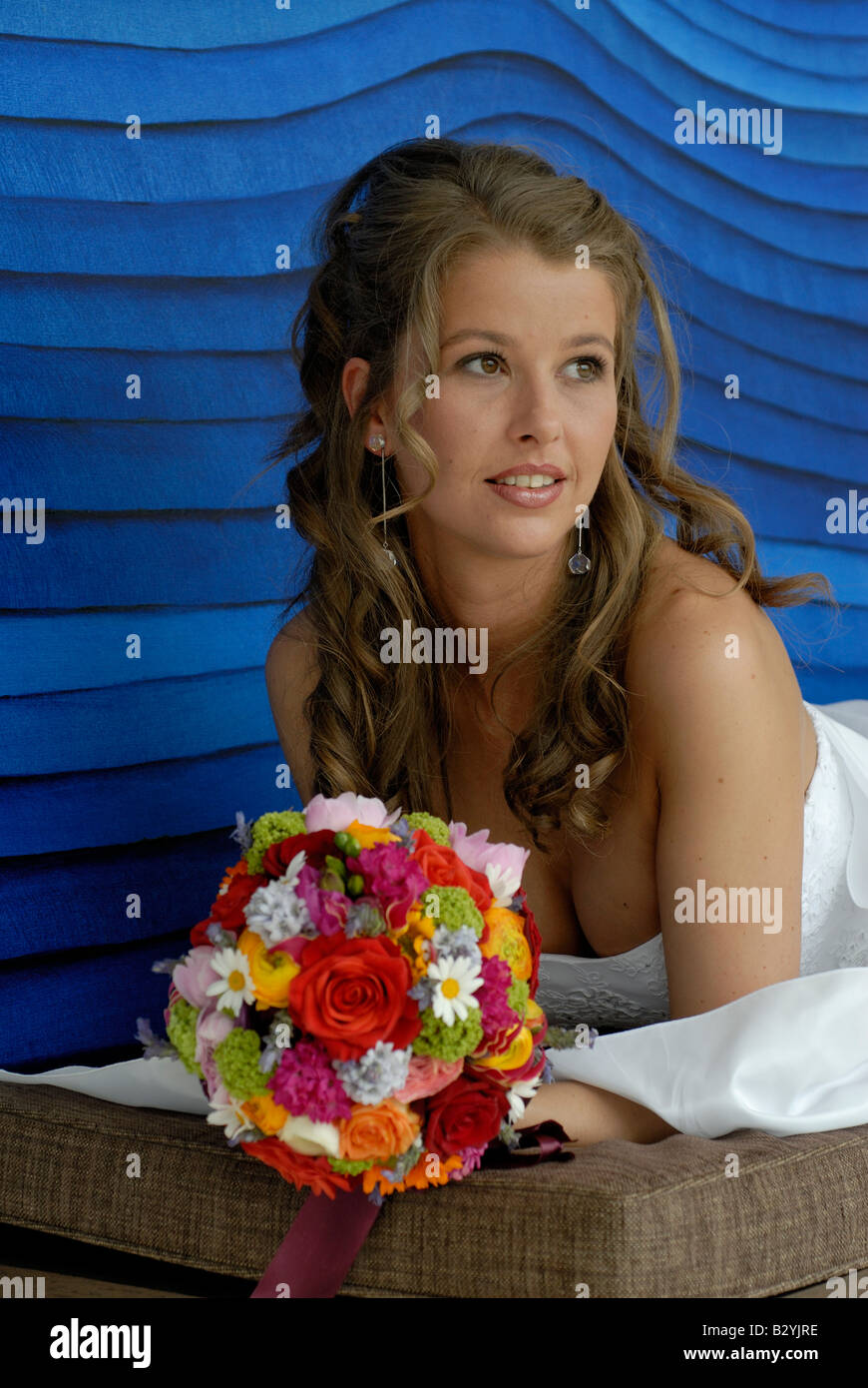 Femme mariée 20s début 30's élégante beauté belles fleurs de mariage robe de mariage blanc sourire long cheveux bouclés Banque D'Images