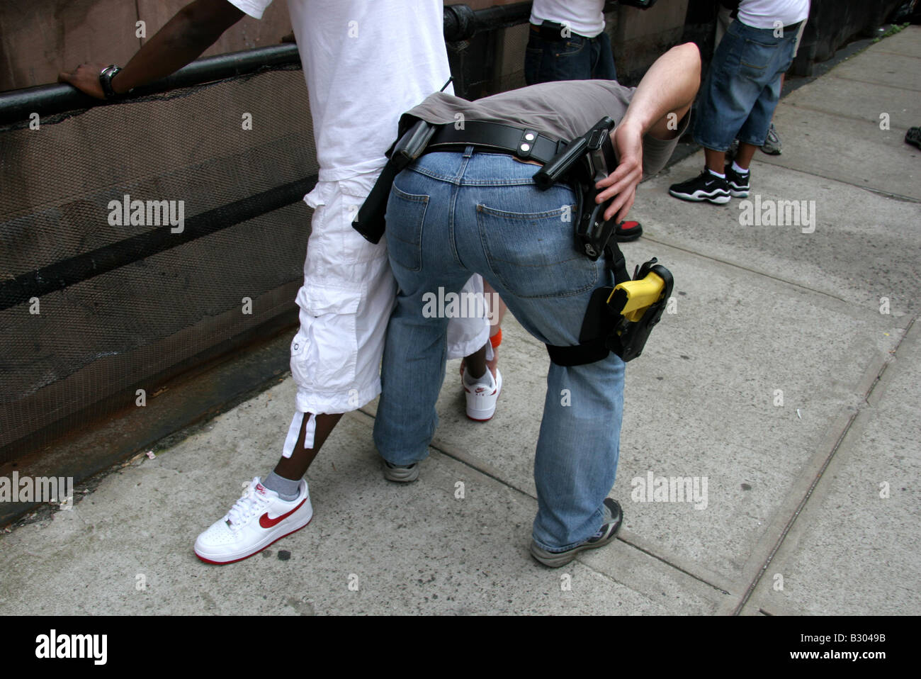 Des détectives de police anti-crime en civil fouillant des suspects à Harlem New York Banque D'Images