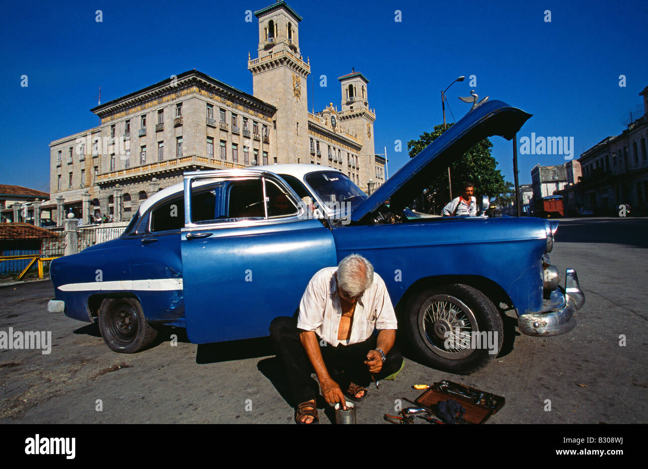 La réparation de l'homme cubains classic car en face de la gare de La Havane, La Havane Viejo, La Vieille Havane, Cuba Zone du patrimoine mondial Banque D'Images