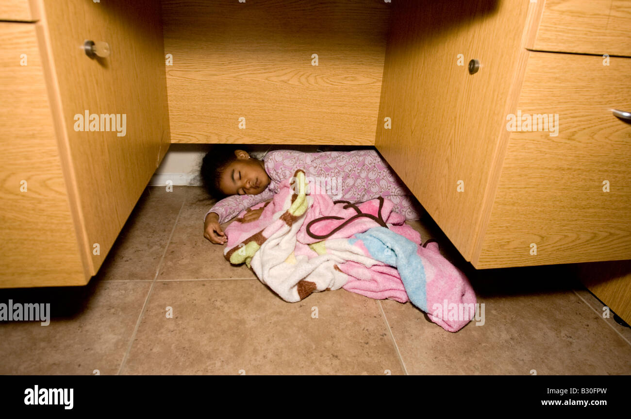 Enfant endormi sur le sol sous un bureau Banque D'Images