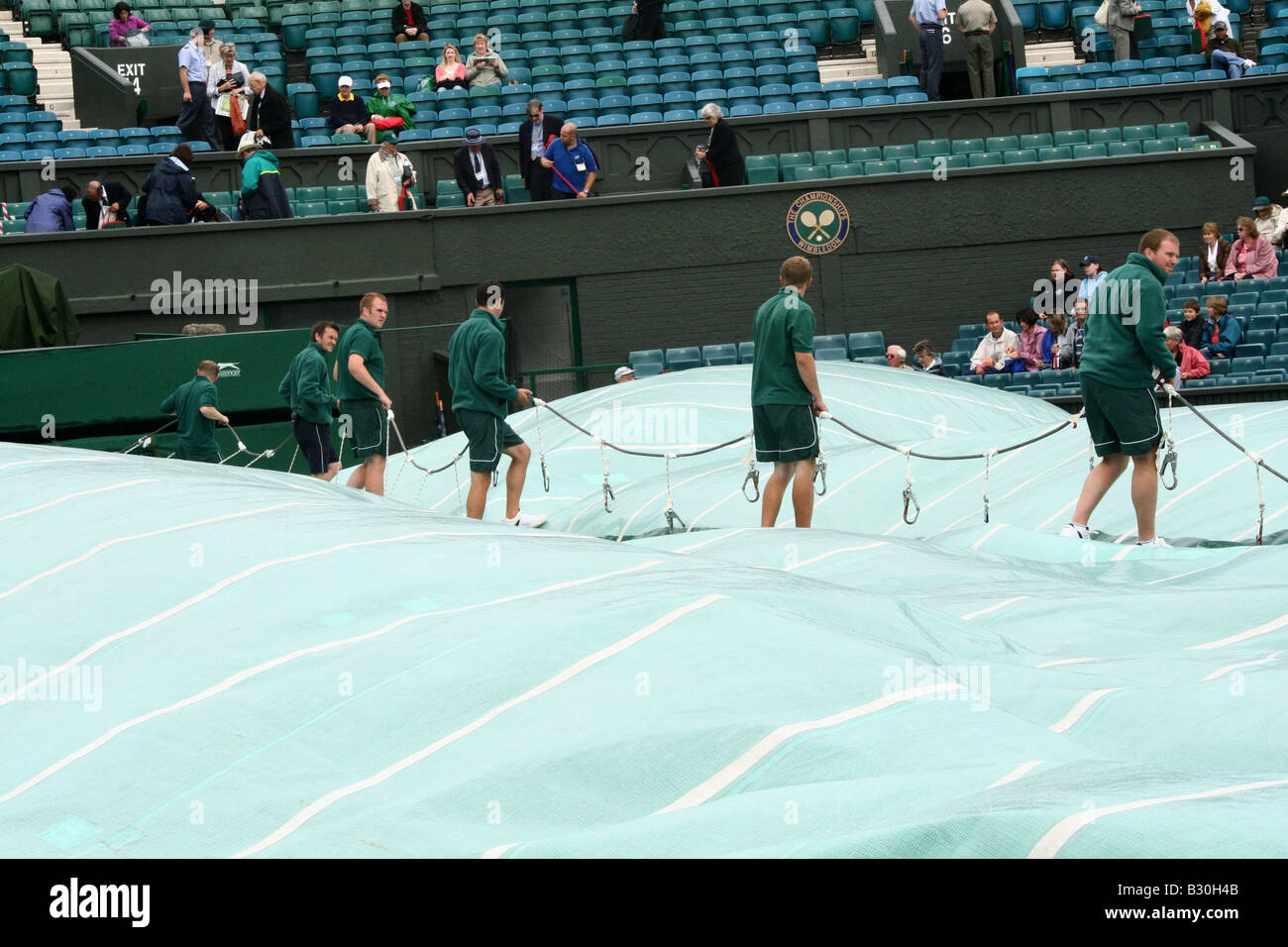 Le personnel au sol se préparent à déposer le couvercle sur le court central après une pluie retard au championnat de tennis de Wimbledon en Angleterre Banque D'Images