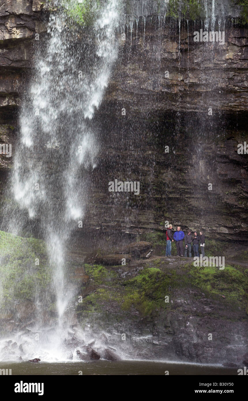 Les gens debout au pied de la cascade de Henrhyd dans le sud du Pays de Galles Banque D'Images