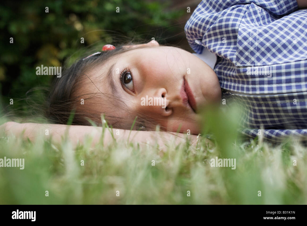 Jeune fille de six ans à l'école primaire le laysin uniforme rêverie herbe London England Banque D'Images