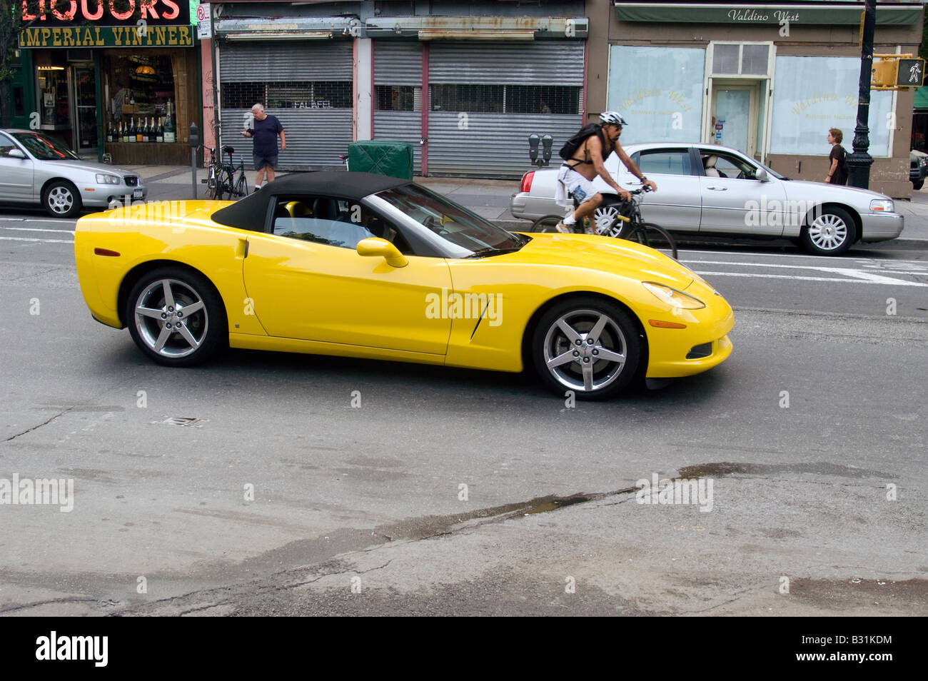 Un dernier modèle de Corvette jaune et un cycliste sur Hudson Street dans Greenwich Village à New York Banque D'Images