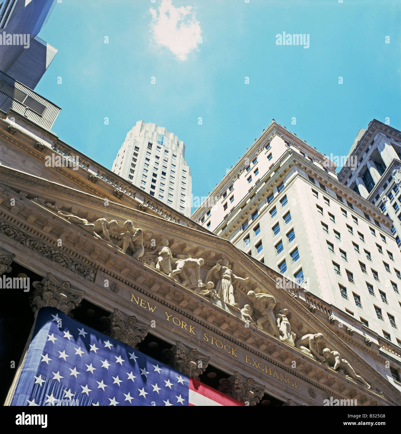 L'extérieur du New York Stock Exchange sur Wall Street avec le drapeau américain et de nuages flottant dans le ciel bleu dans le quartier financier de New York KATHY DEWITT Banque D'Images