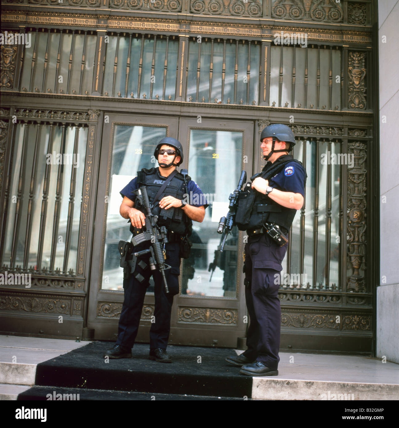 Les policiers américains armés du NYPD flic flip avec la police et les drapeaux américains devant la Bourse de New York sur Wall Street à New York City NYC USA KATHY DEWITT Banque D'Images