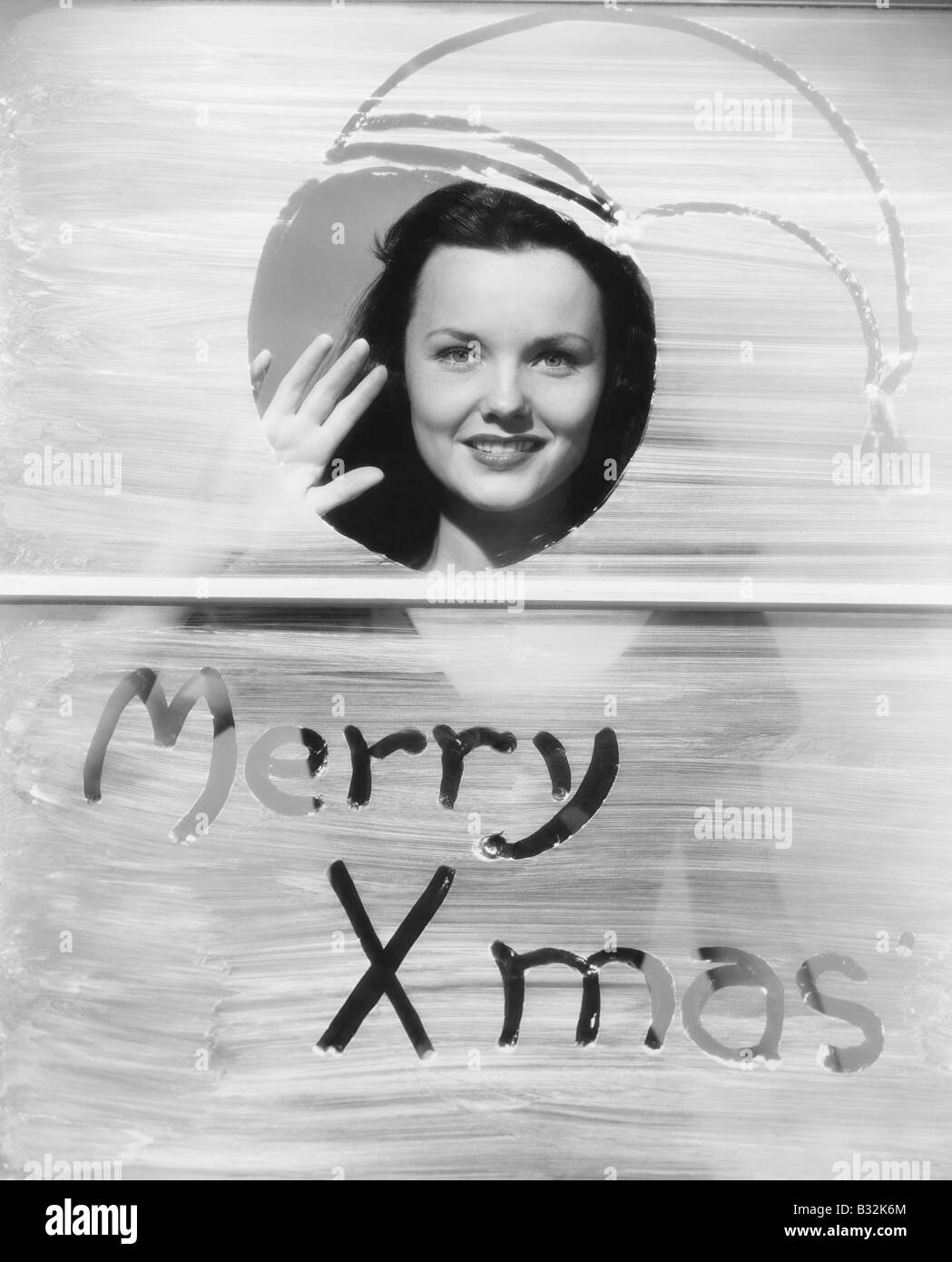Woman waving à fenêtre avec voeux de Noël Banque D'Images