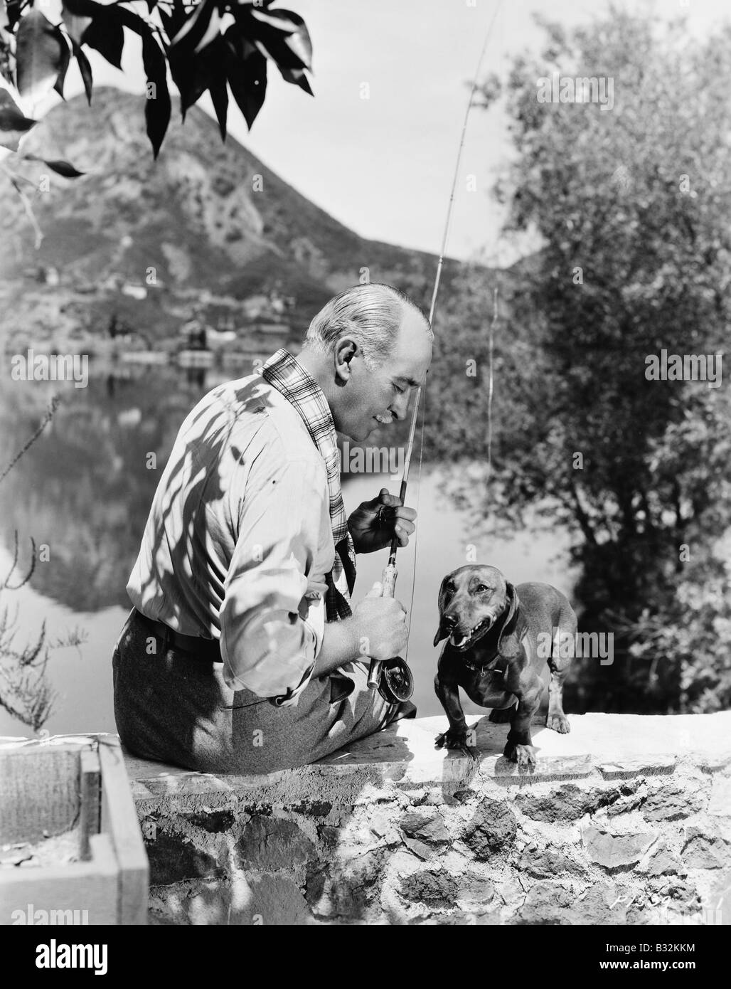 Vieil homme pêche avec petit chien Banque D'Images