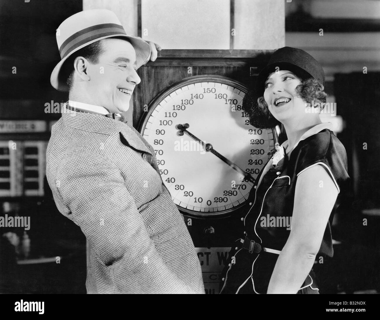 Playful couple standing on scale Banque D'Images