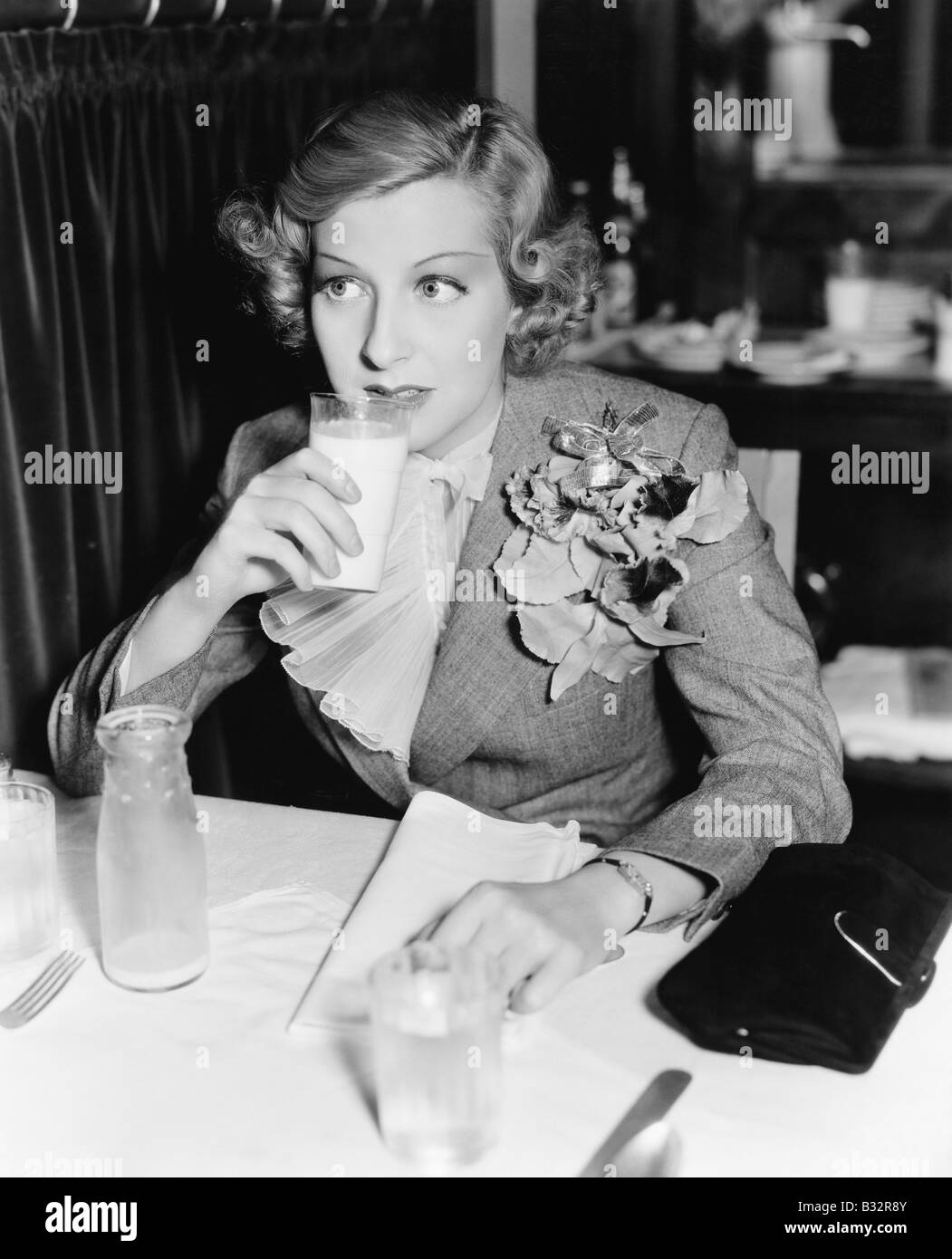 Jeune femme assise à une table dans un restaurant boire du lait Banque D'Images
