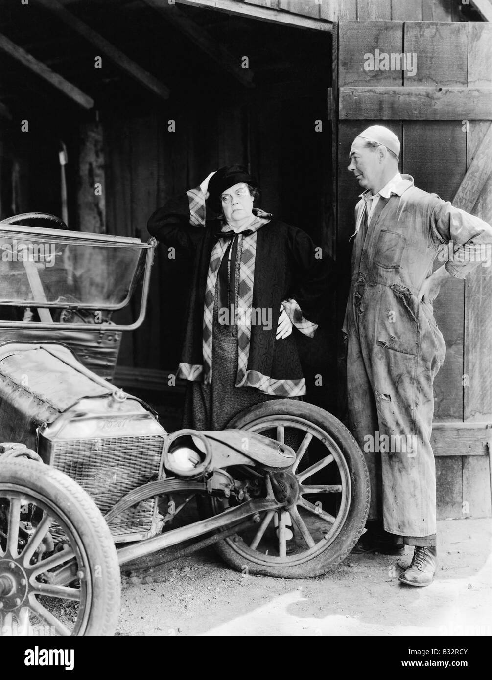 Homme et Femme regardant une voiture accidentée dans la grange Banque D'Images