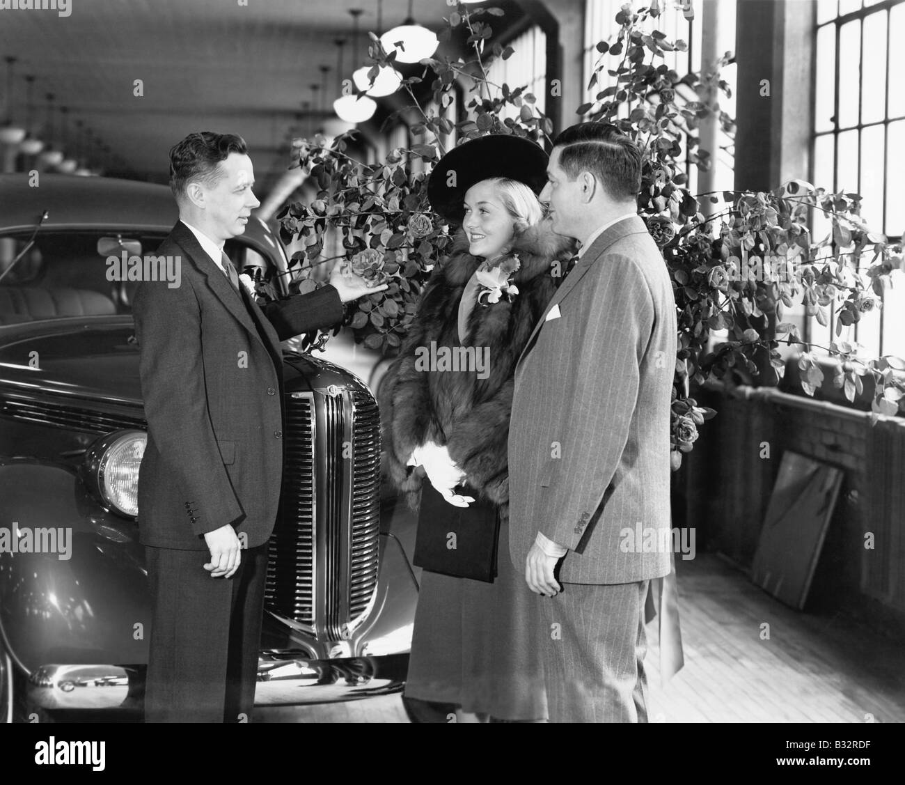 L'homme et la femme debout dans une voiture d'exposition de parler à un vendeur Banque D'Images