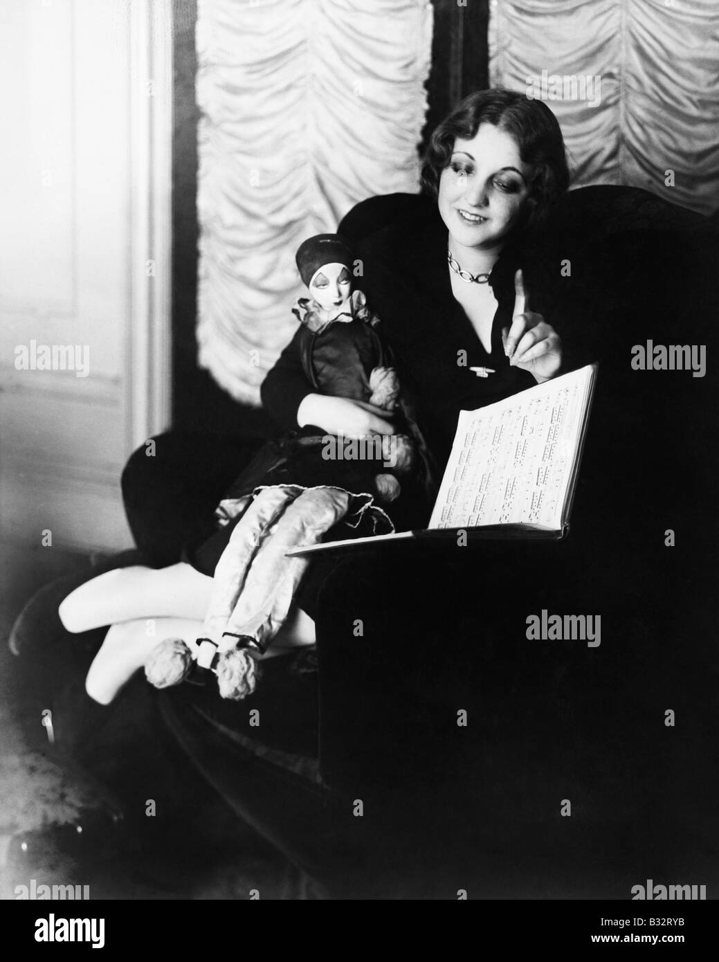 Femme assise dans un fauteuil avec sa marionnette en lisant un livre Banque D'Images