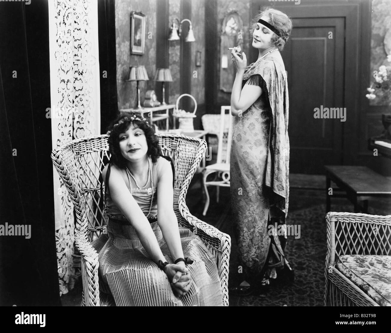 Femme assise dans un fauteuil avec une autre femme fumer une cigarette à l'arrière-plan Banque D'Images