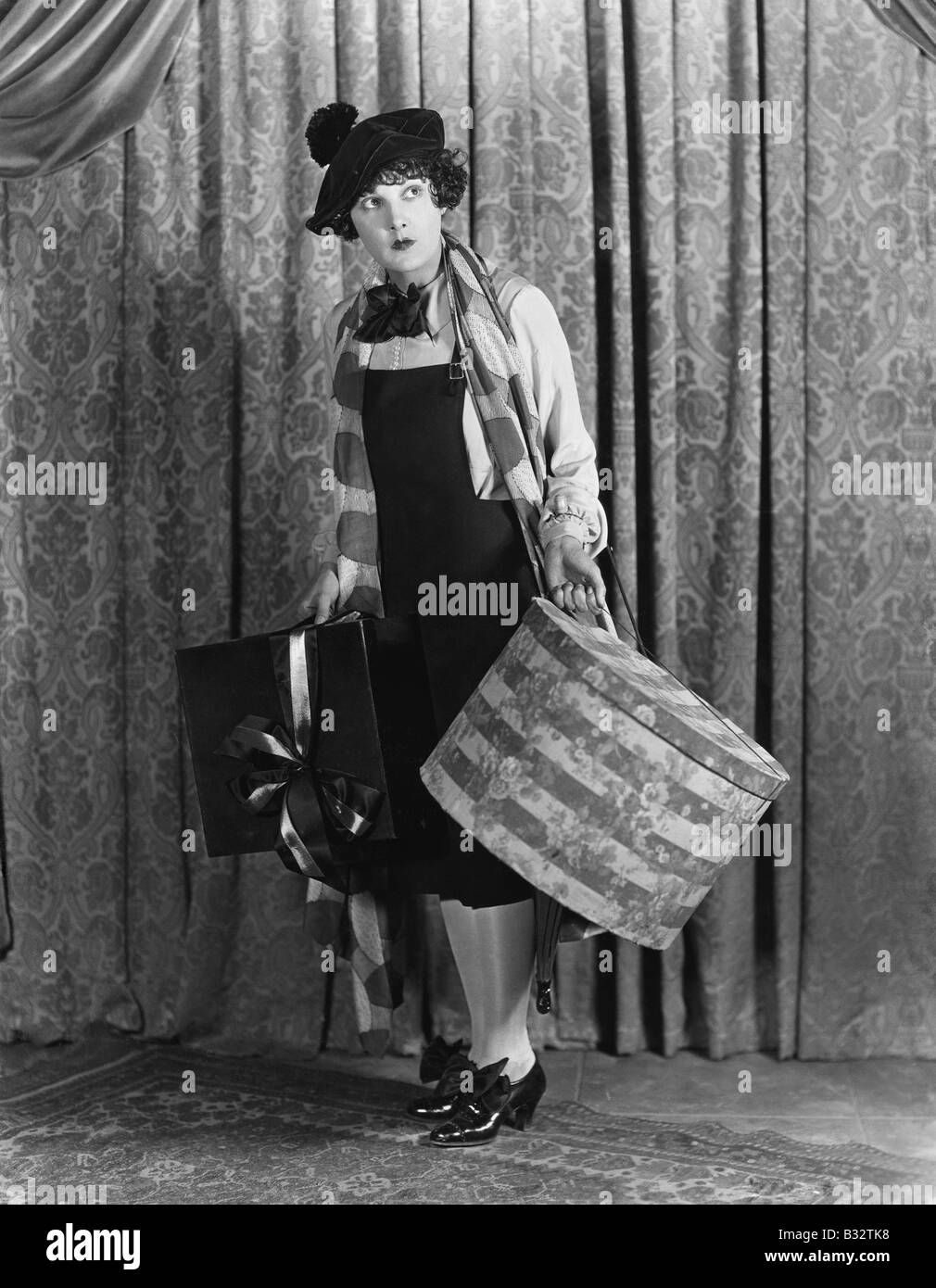 Femme dans un béret tenant une boîte à chapeau et présente Banque D'Images