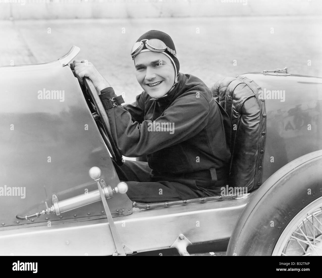 Jeune homme assis dans une voiture de course avec un grand sourire Banque D'Images